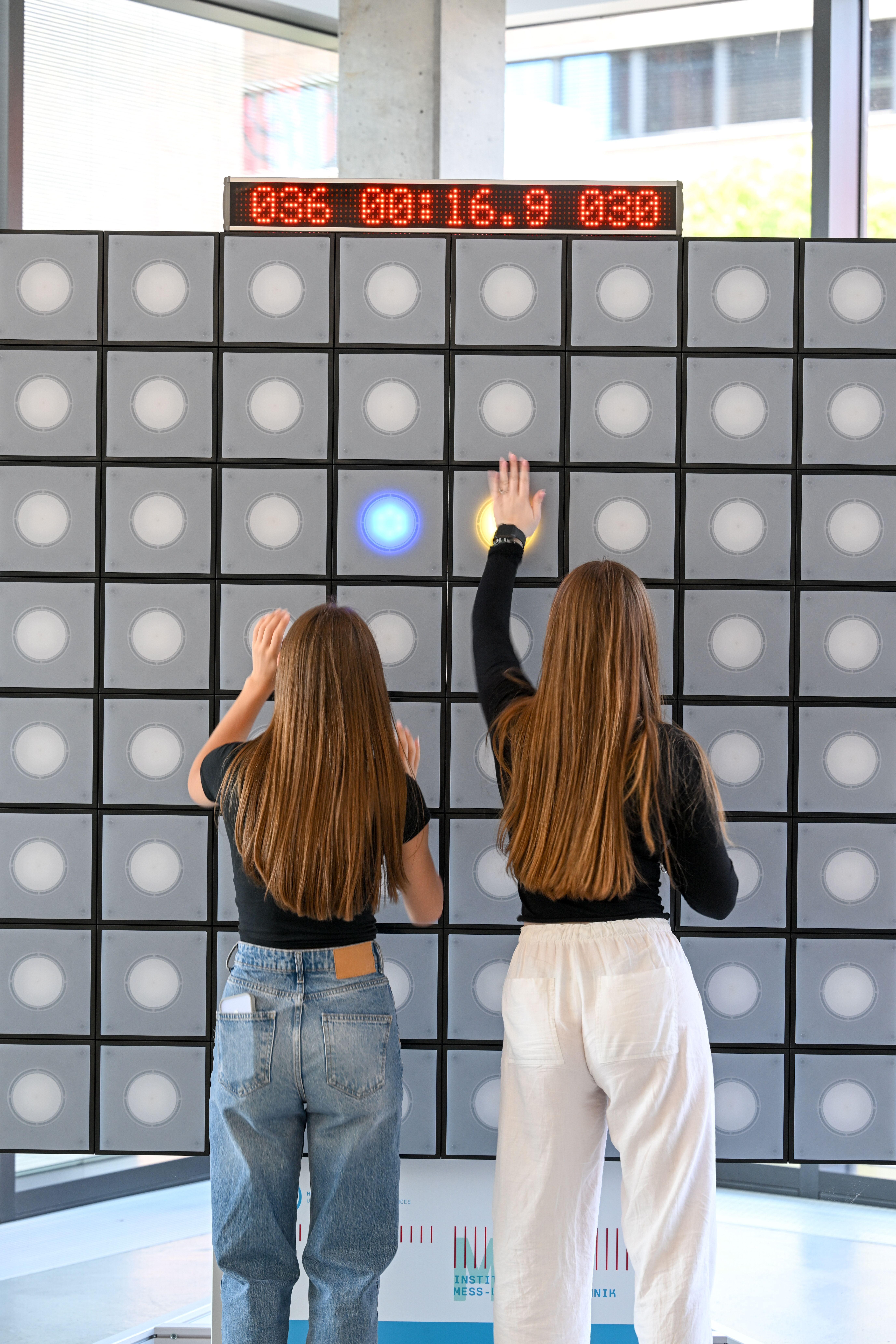 Zwei Personen spielen ein Spiel auf der T-Wall.