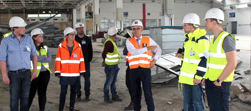 Studierende und ein Professor auf einer Baustelle während einer Exkursion.