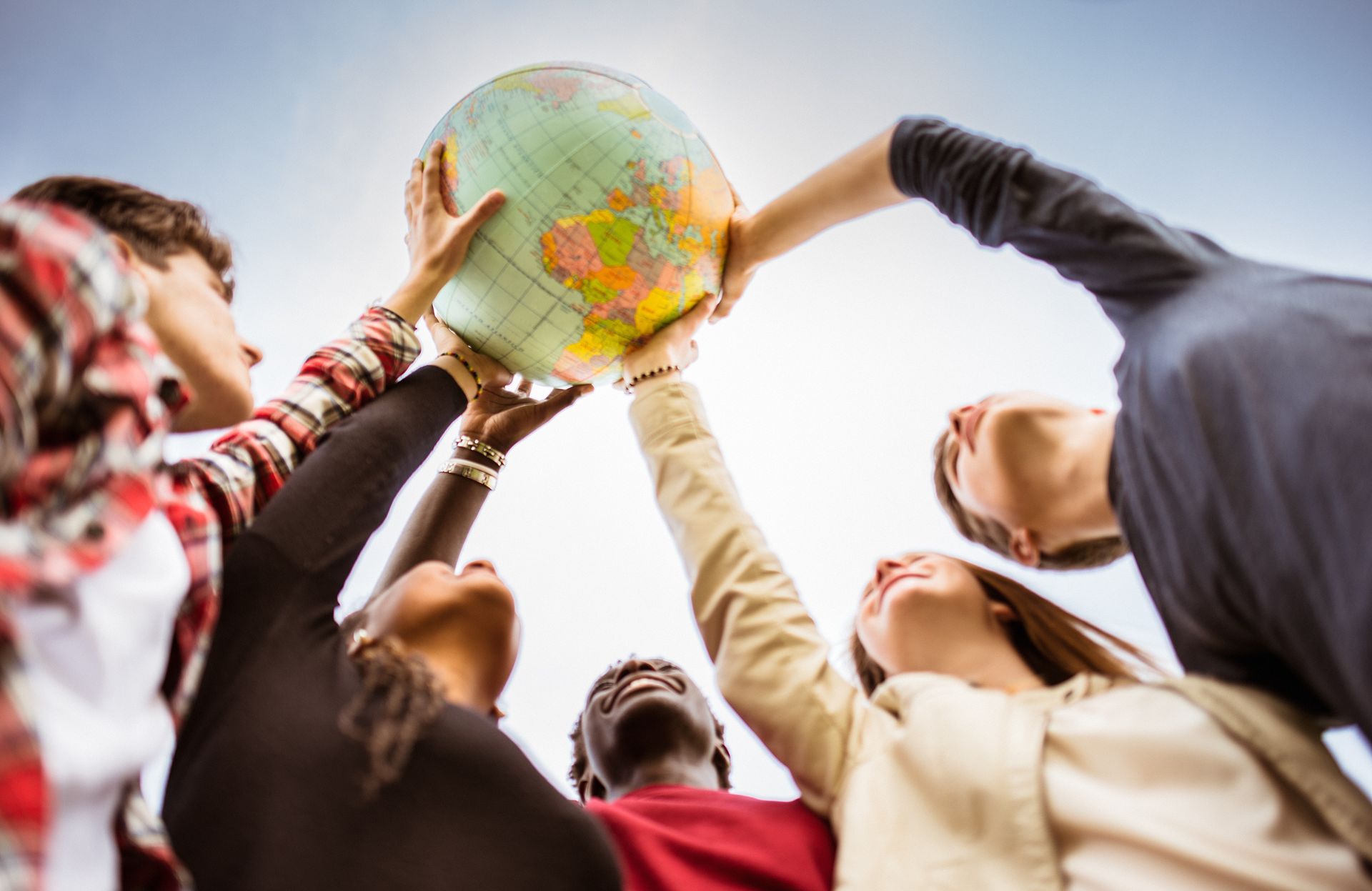 Stockfoto – Jugendliche halten gemeinsam einen Globus in die Höhe: Symbolbild für internationale Zusammenarbeit, Vielfalt, Weltoffenheit und globale Bildung.