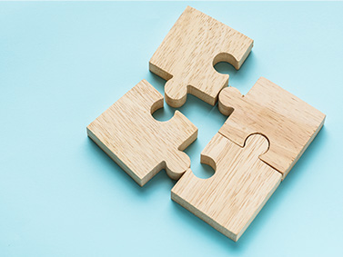 vier hölzerne Puzzleteile auf blauem Hintergrund