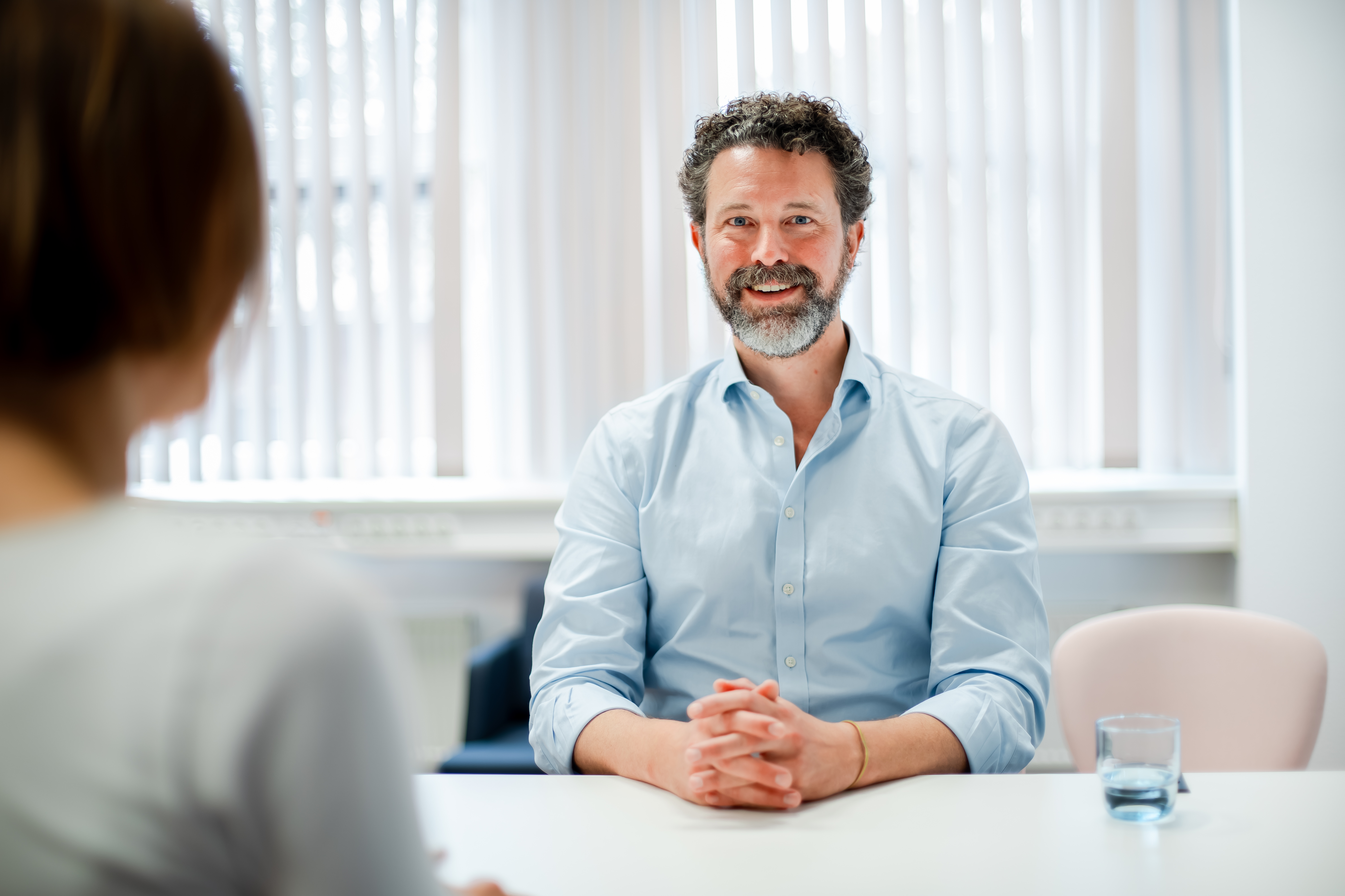 Auf dem Foto ist ein Mann mit grauem lockigen Haar zu erkennen, der lächelnd in die Kamera schaut.