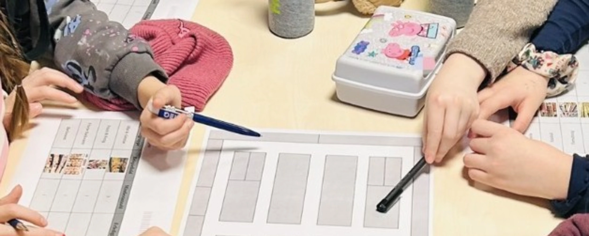 Schüler:innen arbeiten gemeinsam an einem Arbeitsblatt zur Regal- und Produktplatzierung und markieren mit Stiften verschiedene Bereiche eines Supermarktlayouts.