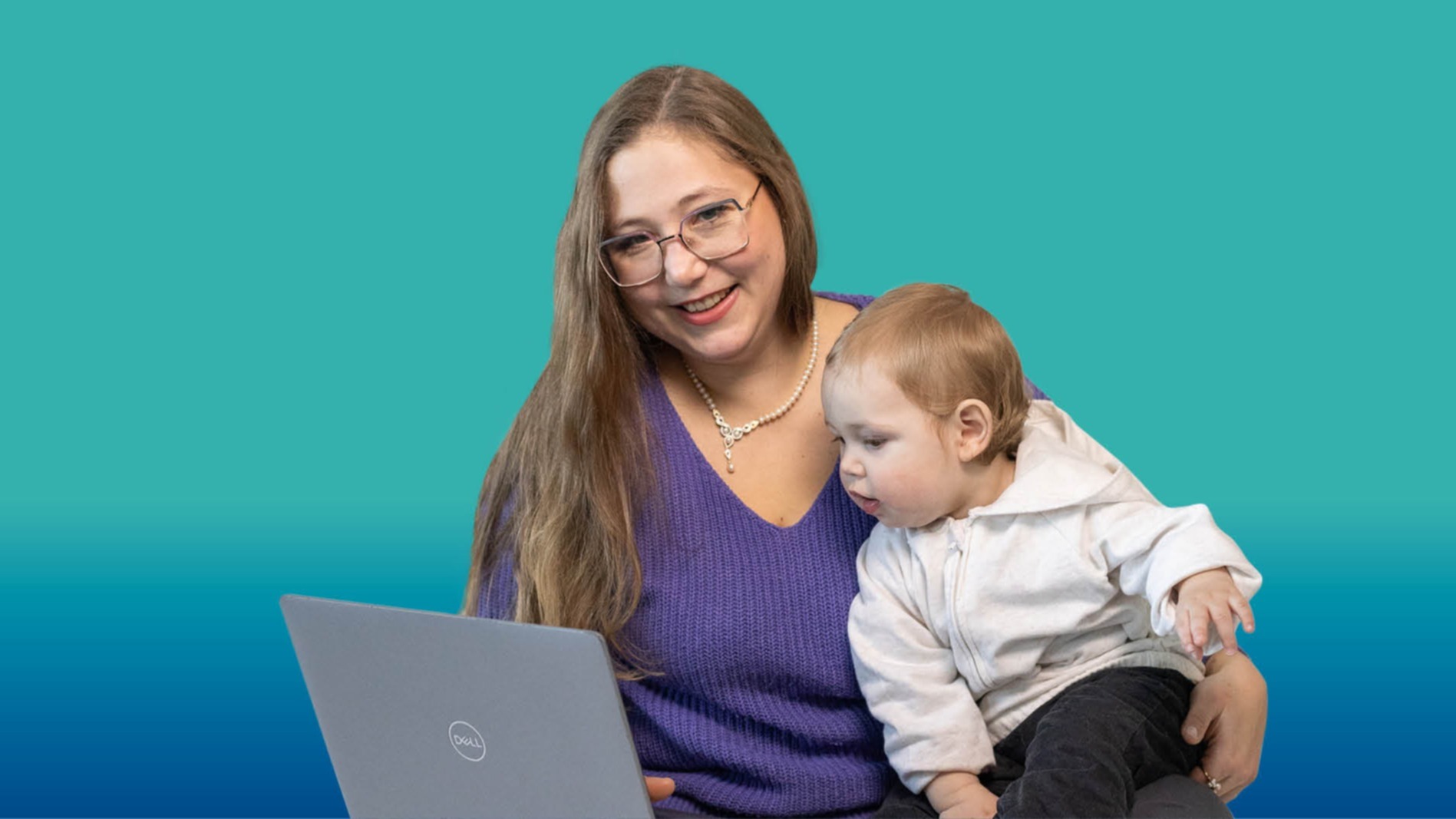 Junge Frau mit Brille und Baby auf dem Schoß schaut gemeinsam mit dem Kind auf einen Laptop