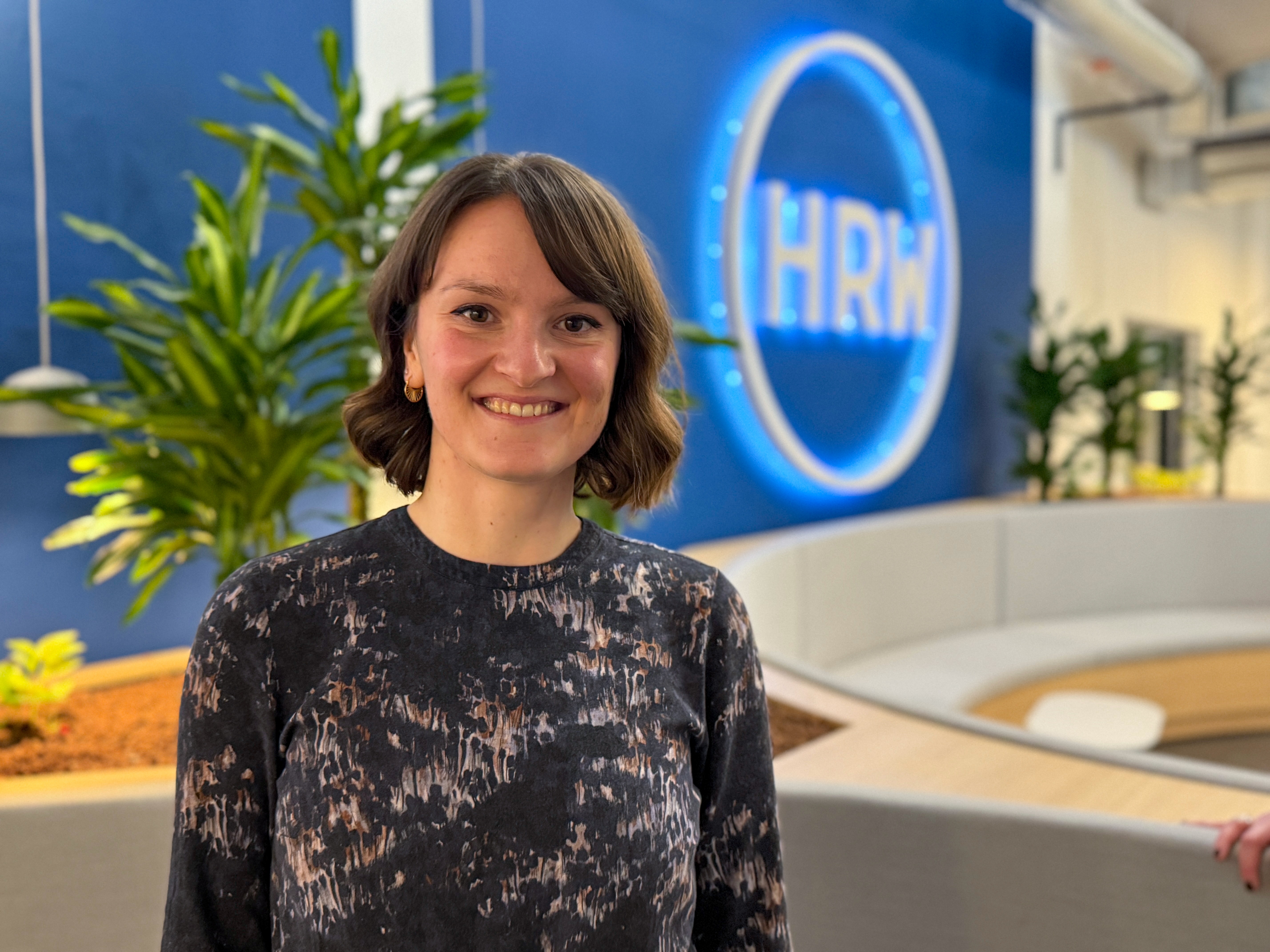 Magda Lukusz im Porträt. Im Hintergund ist das HRW Logo zu sehen
