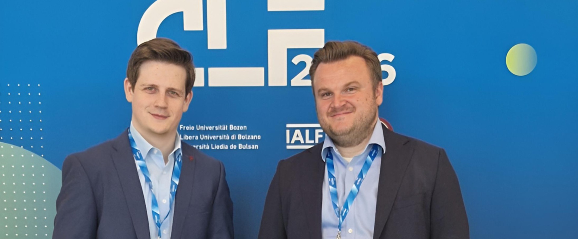 Prof. Dr. Friedrich Morlock und Julian Grzywaczyk stehen vor dem Banner der Konferenz  CLF2026.