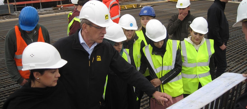 Das Bild zeigt eine Gruppe von Menschen mit Baustellenhelmen auf einer Baustelle