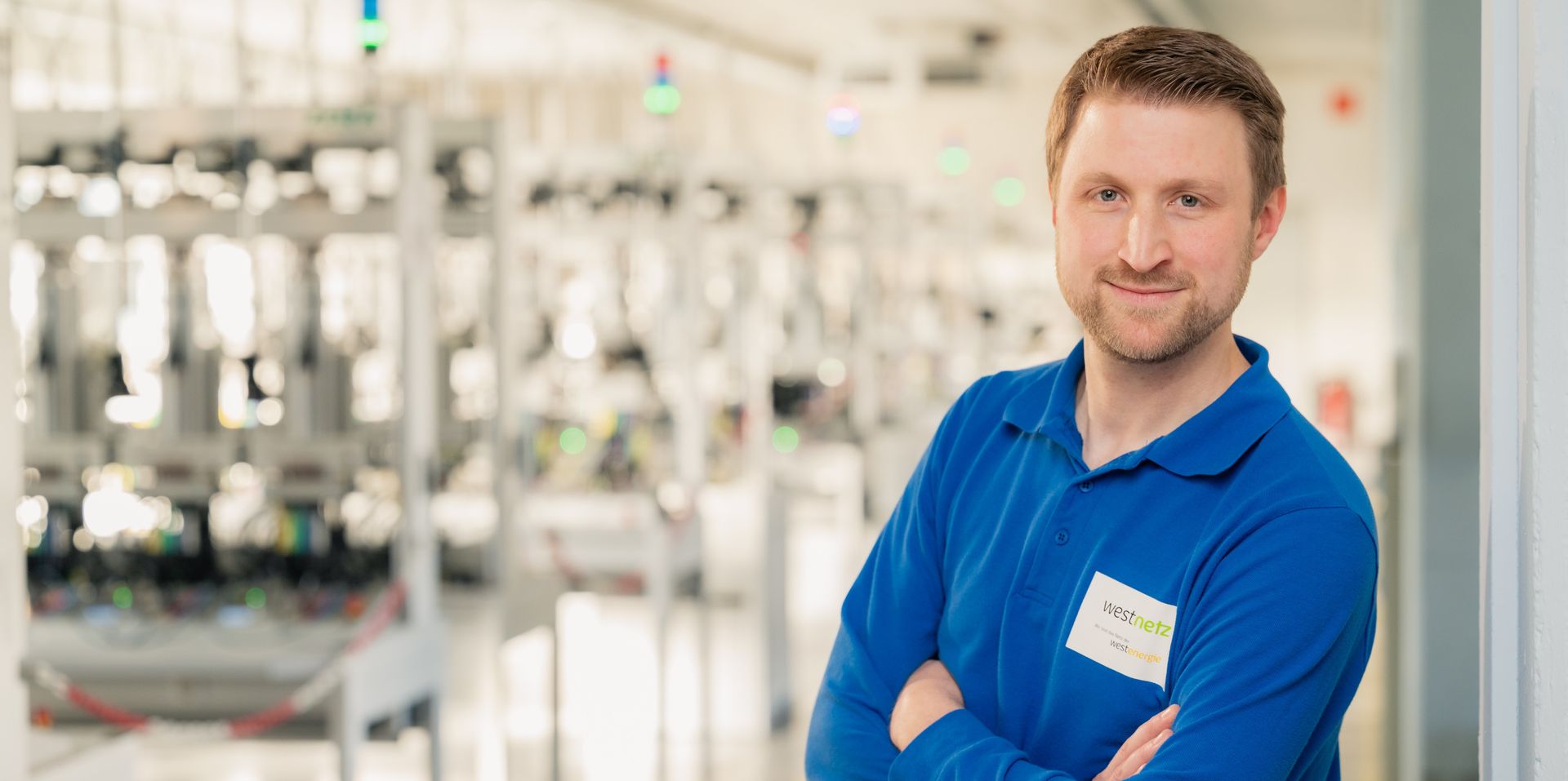 HRW Alumnus Johannes Reidick steht vor einem Prüfraum bei seinem Arbeitgeber Westnetz.