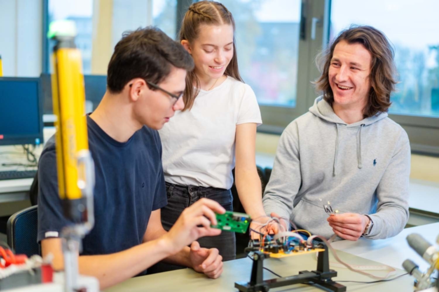 Drei Studierende der Sicherheitstechnik arbeiten an einer Platine.
