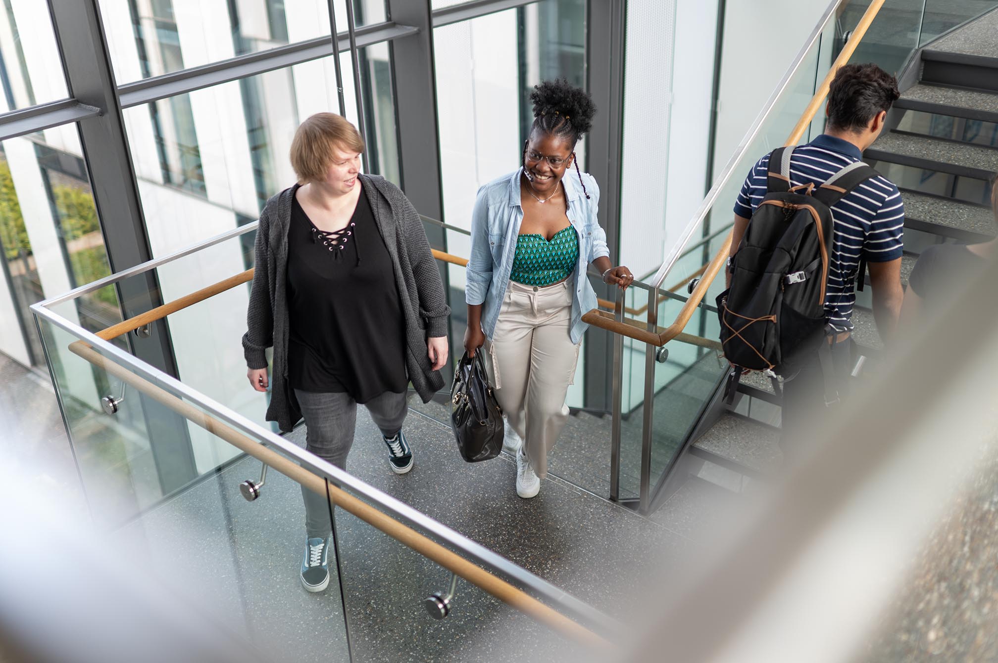 Zwei Frauen und ein Mann nehmen die Treppen im Campus Bottrop.
