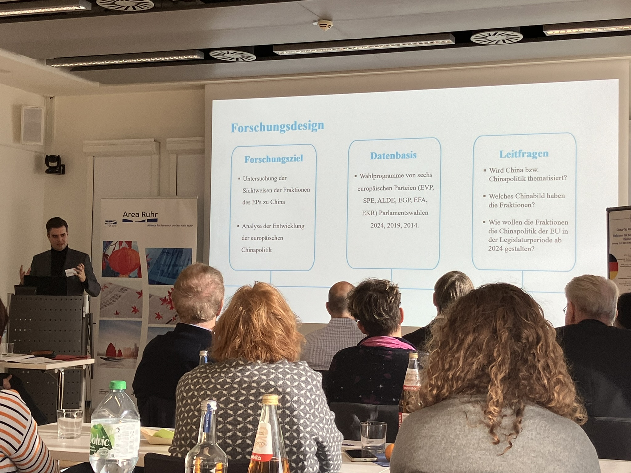 Das Foto zeigt Tim Hildebrandt (vortragende Person), der vor einem Publikum einen Vortrag hält.
