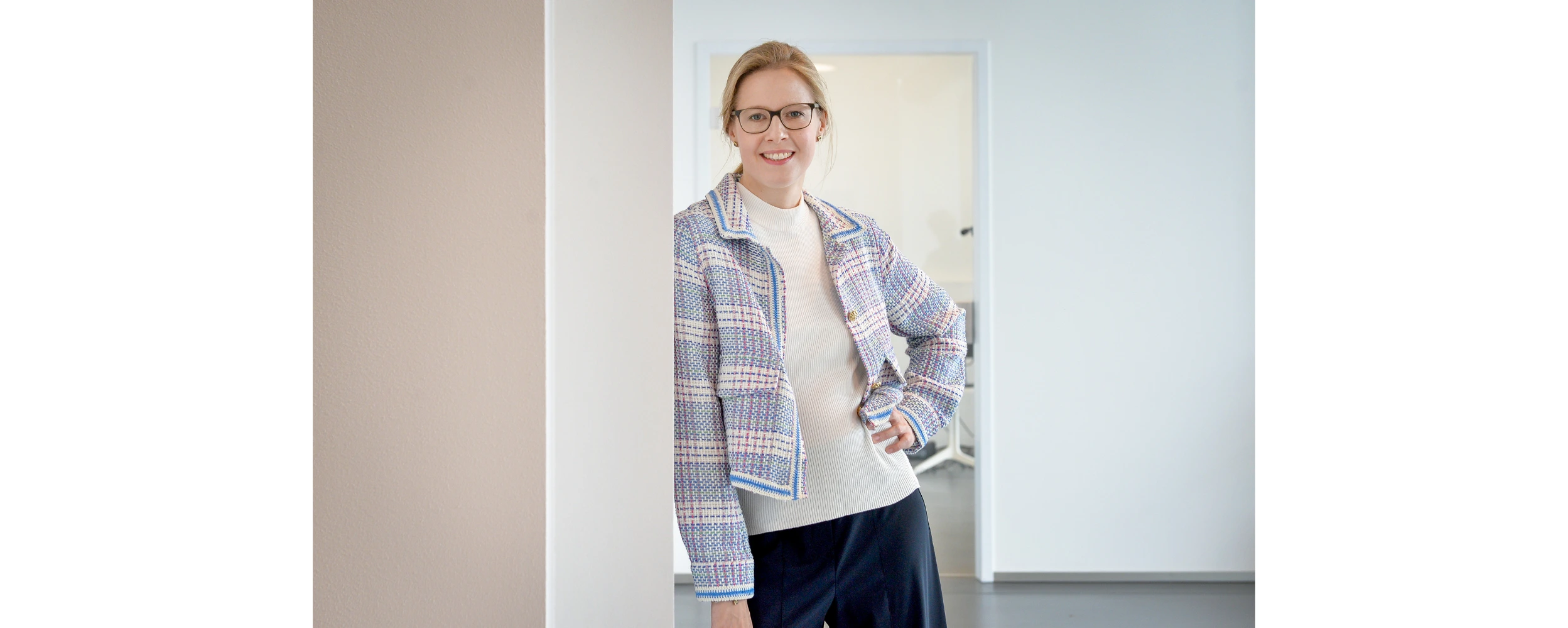 Prof. Dr. Julia Thalmann lehnd einer Wand mit der Hand in der Hüfte gesützt.
