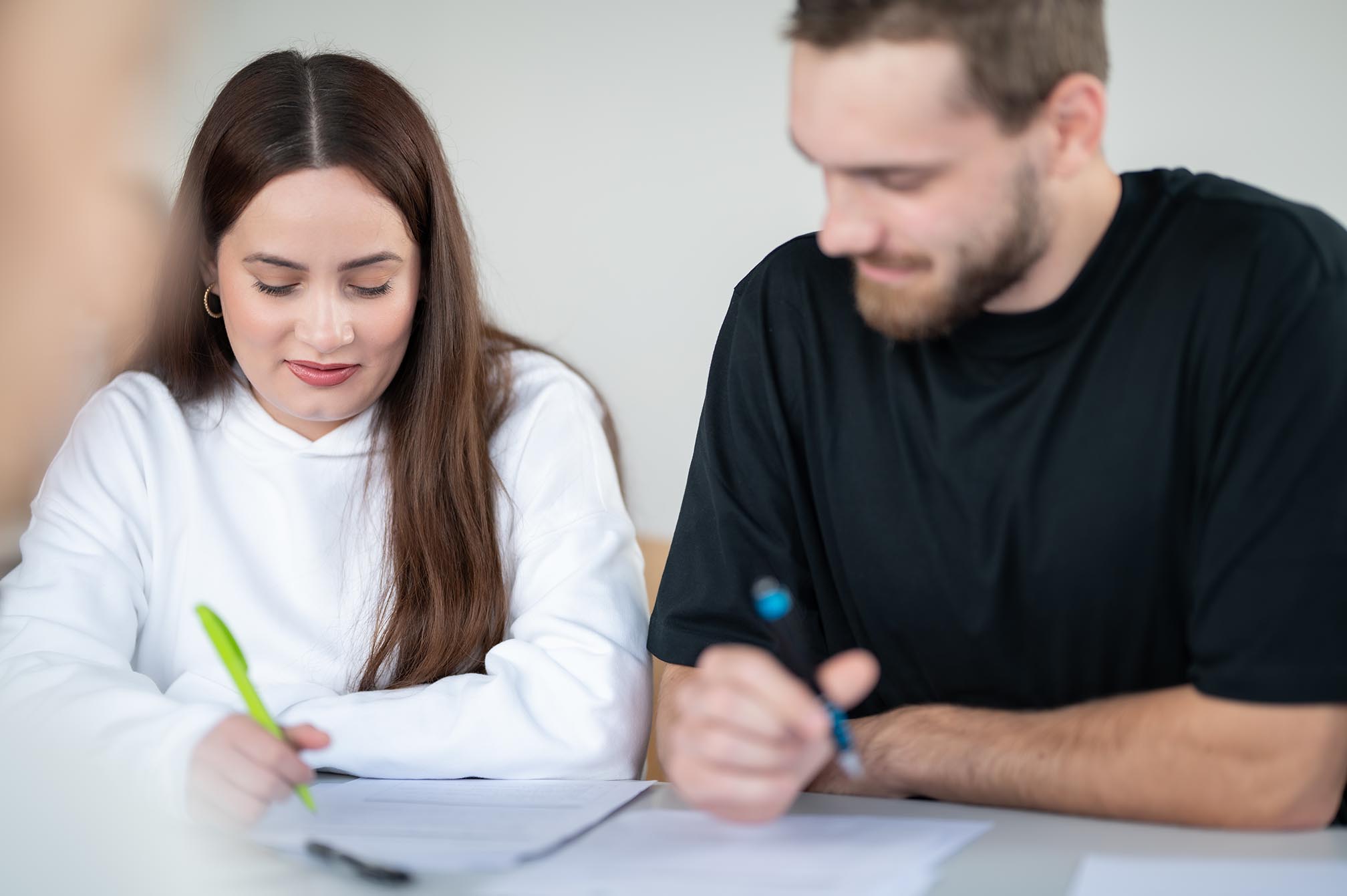 Zwei Studenten sitzen am Schreibtisch, schreiben auf Papieren.