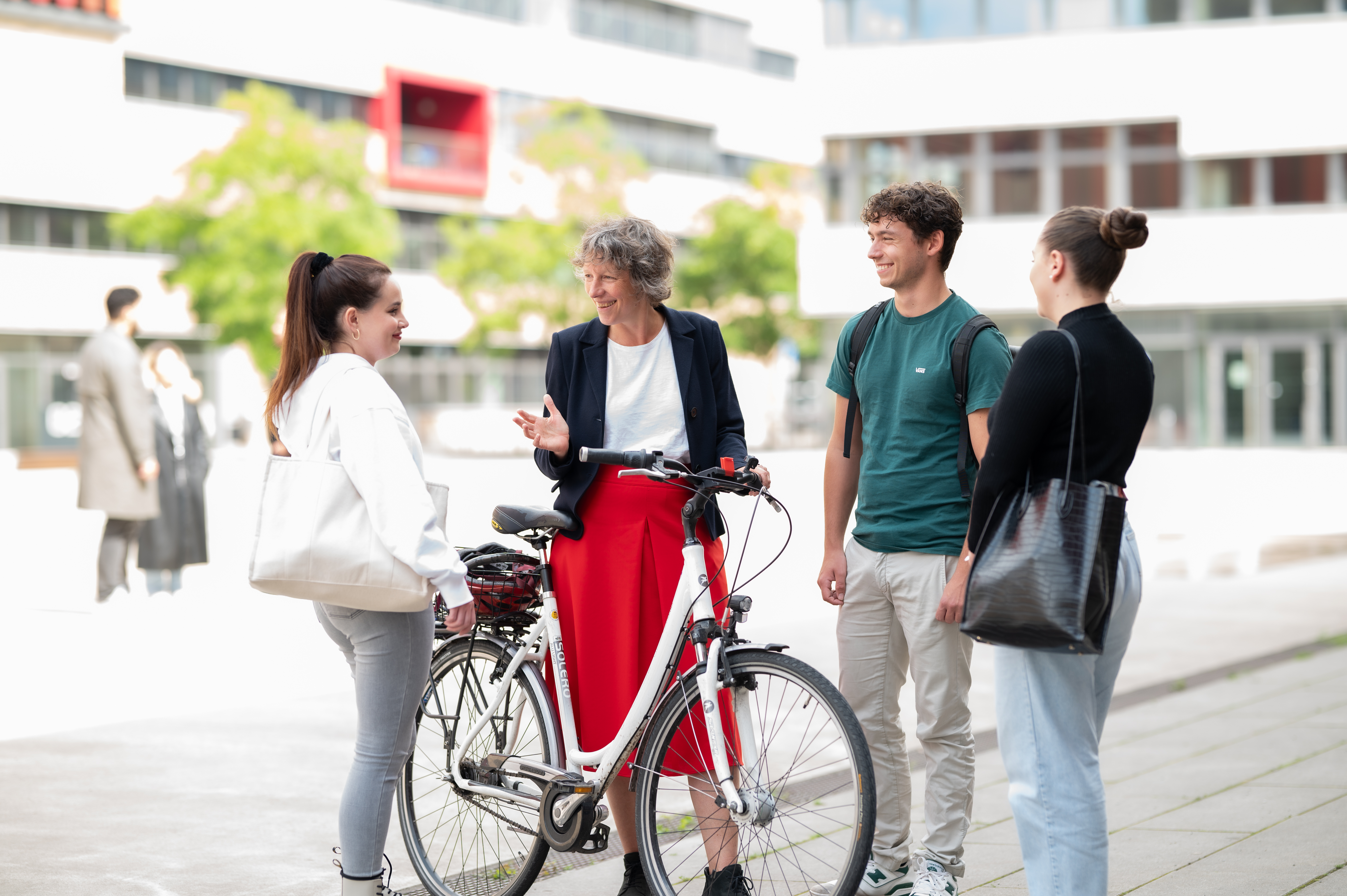 Drei Studierende und die Päsidentin der Hochschule mit einem Fahrrad auf dem Campus