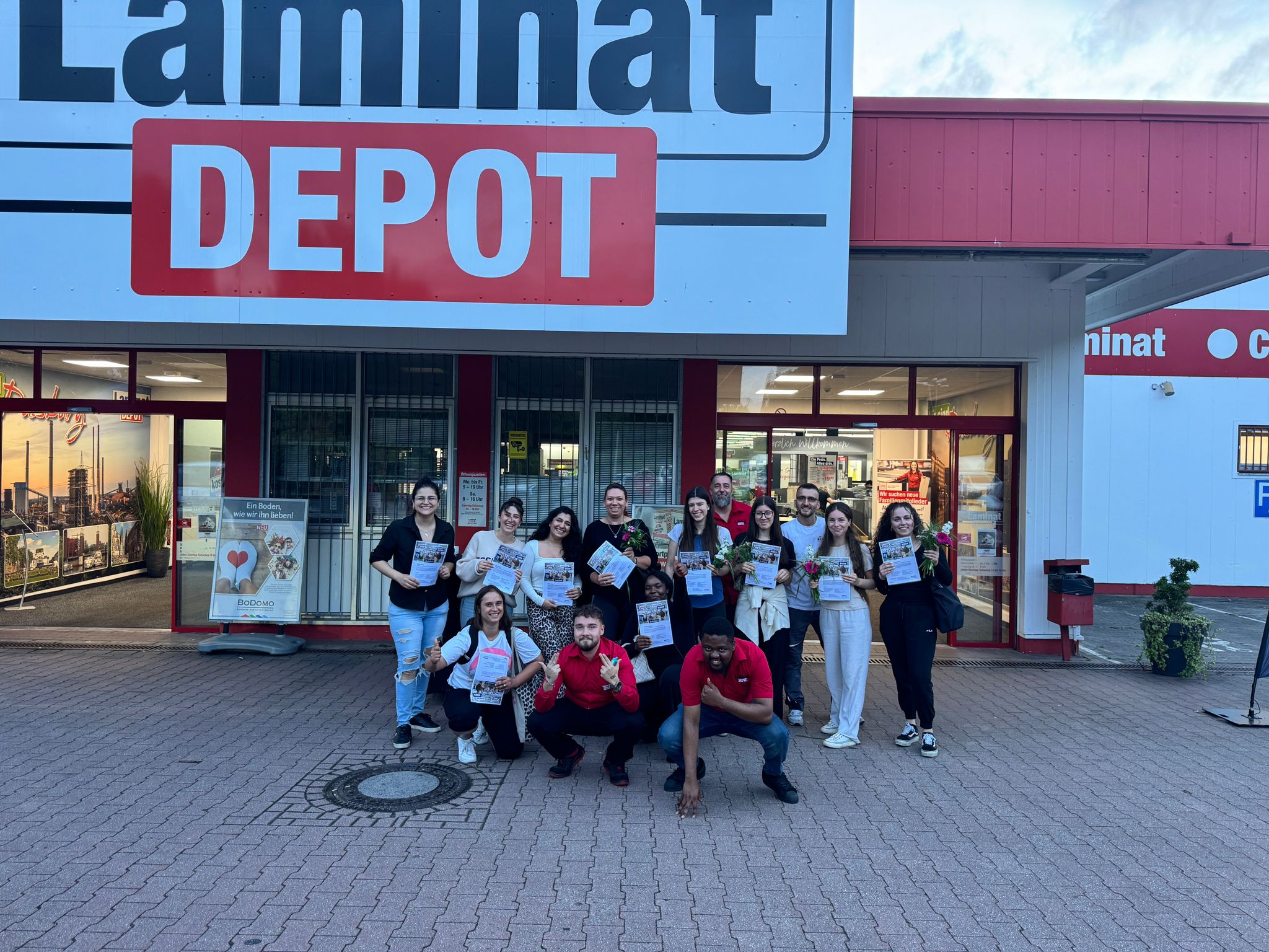 Laminat Depot Duisburg, Teilnehmerinnen vor Eingang mit Urkunde und Mitarbeiter