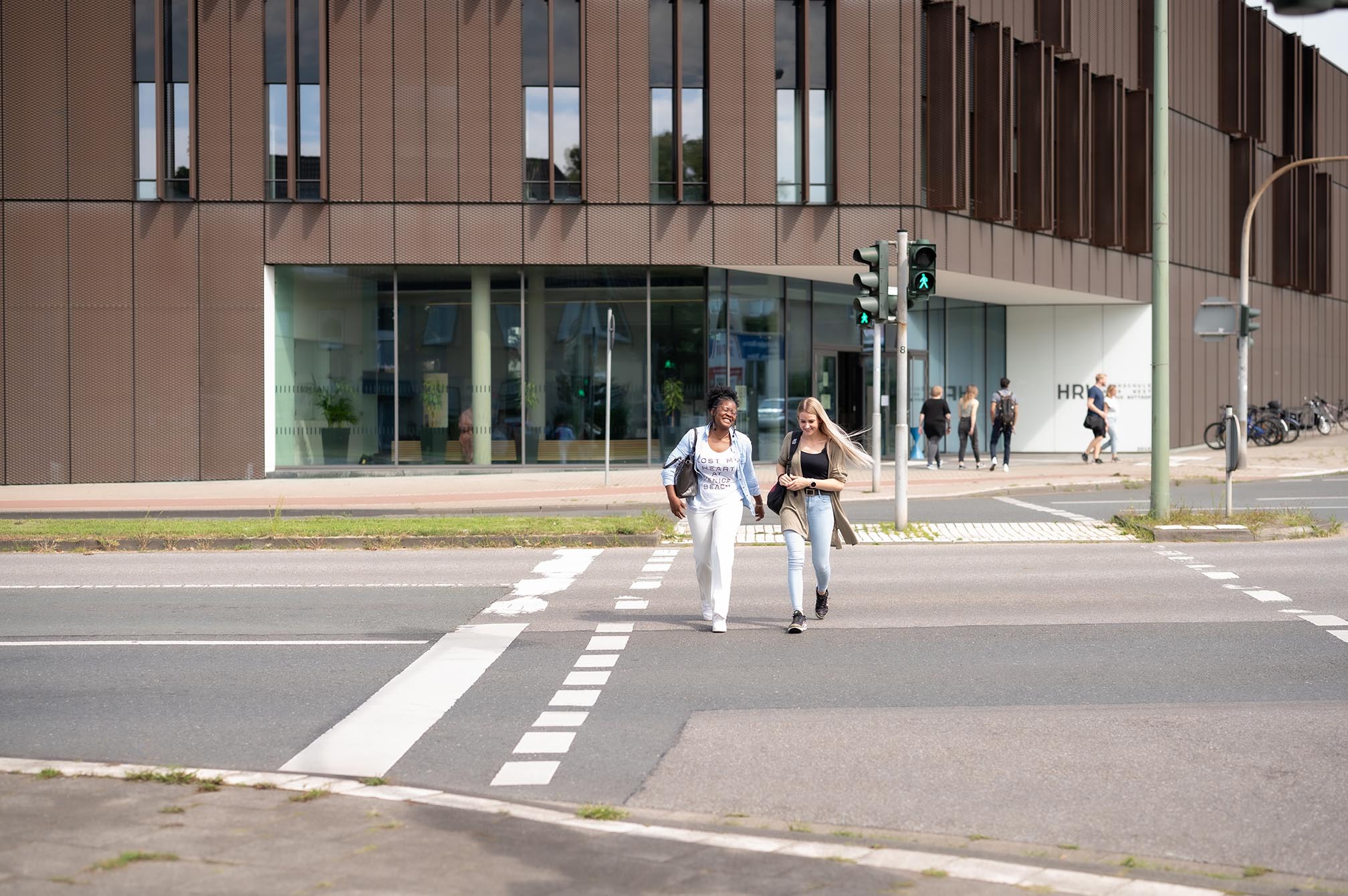 Zwei Personen laufen über die Ampel vor dem Campus in Bottrop
