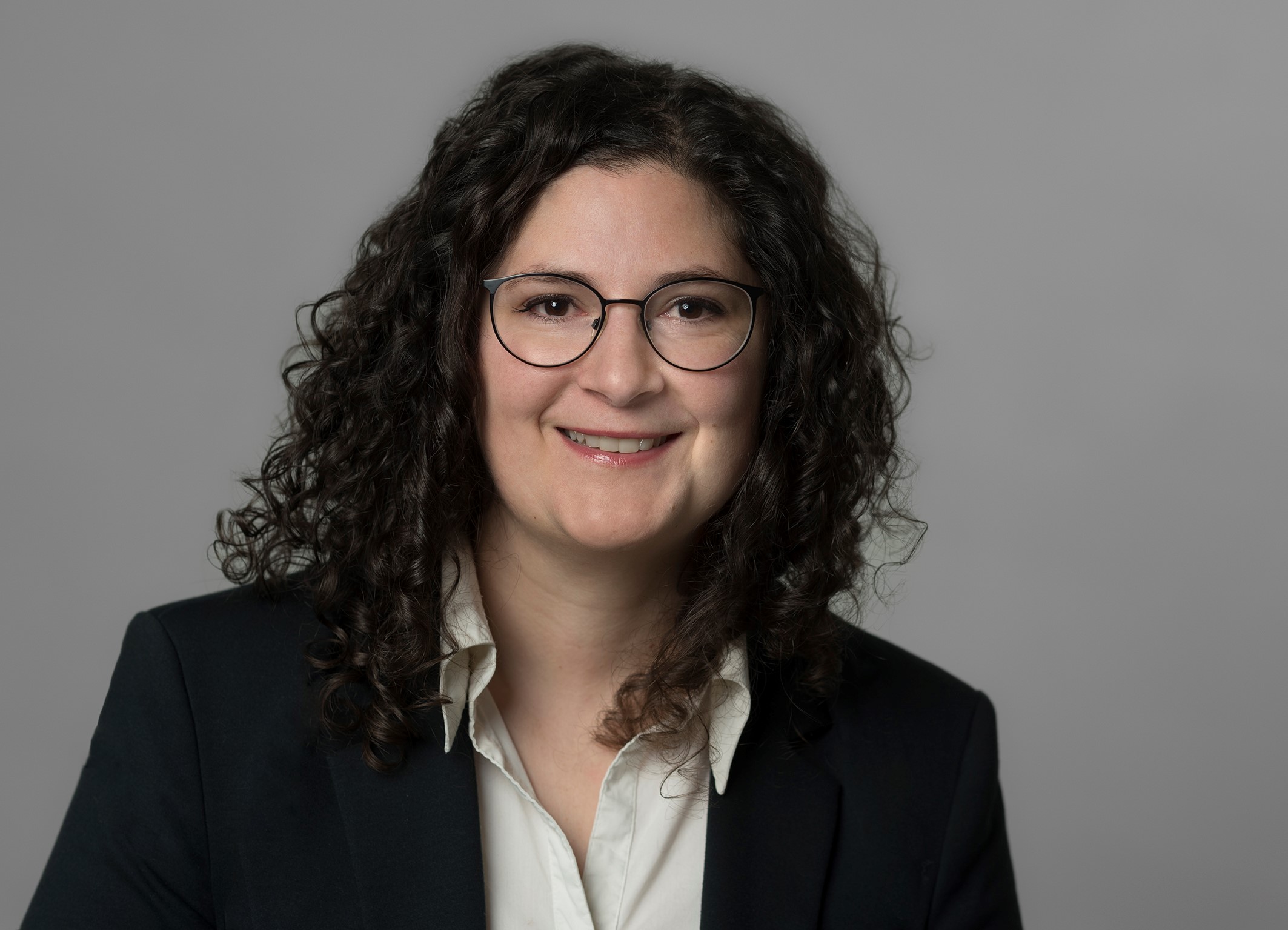 Auf dem Foto ist eine Frau mit dunklen Haaren und Brille zu erkennen.