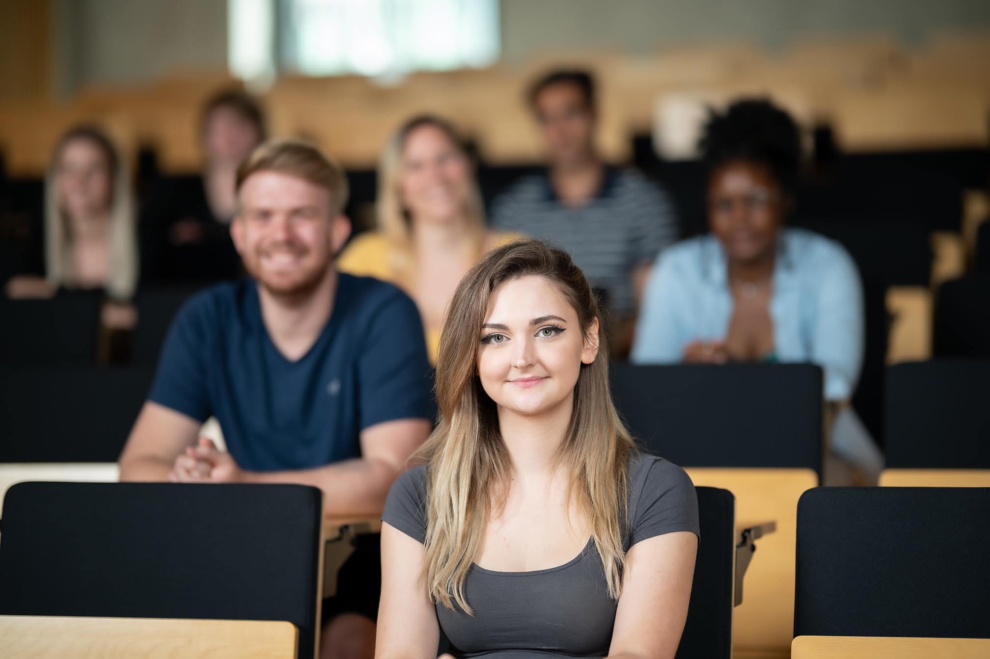 Eine Studentin sitzt in einem Hörsaal mit anderen Studierenden im Hintergrund auf dem Campus Bottrop.