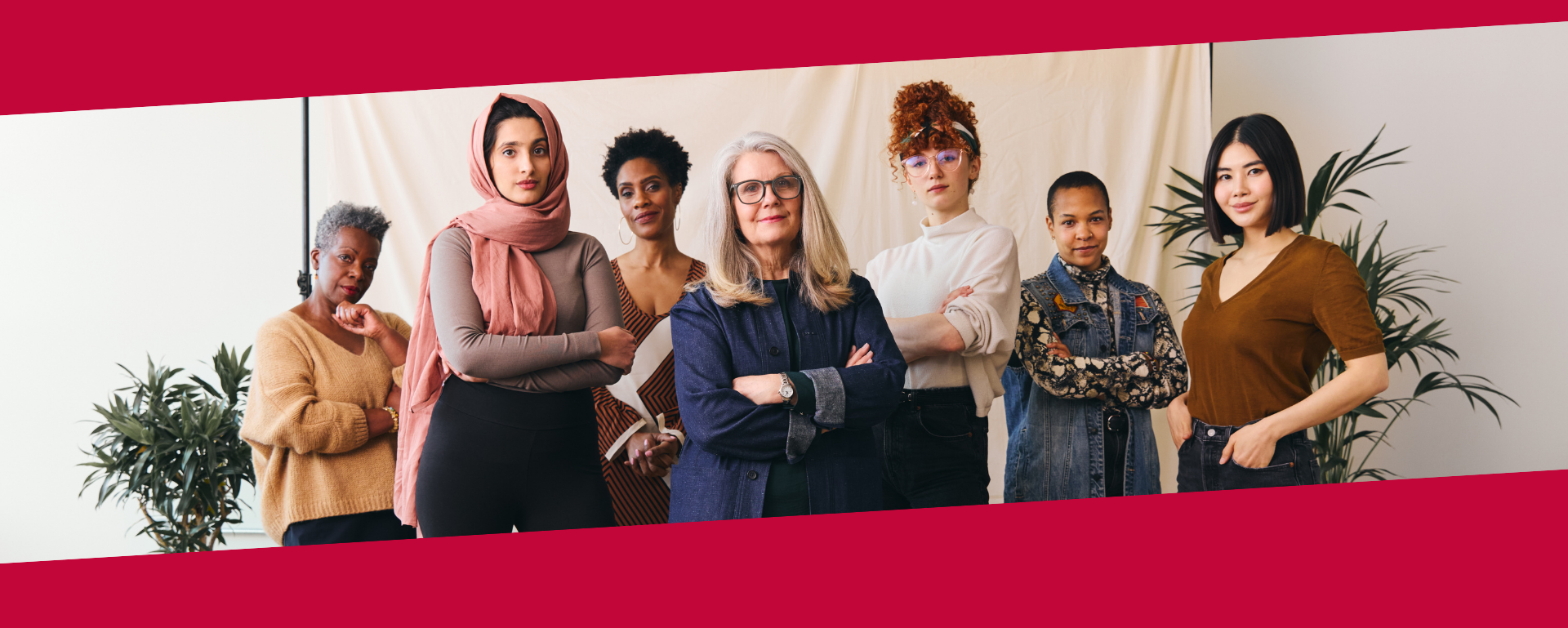 Sieben Frauen stehen nebeneinander, selbstbewusst mit verschränkten Armen und schauen in die Kamera