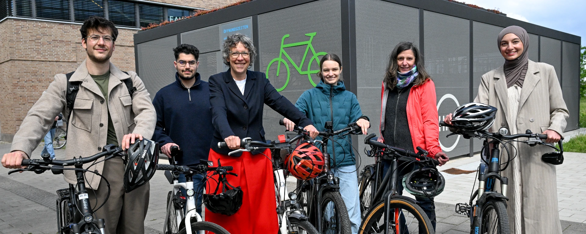 Mehrere Studierende und Beschäftigte der HRW stehen mit der Präsidentin Susanne Staude mit Fahrrädern vor dem Fahrrad-Parkhaus