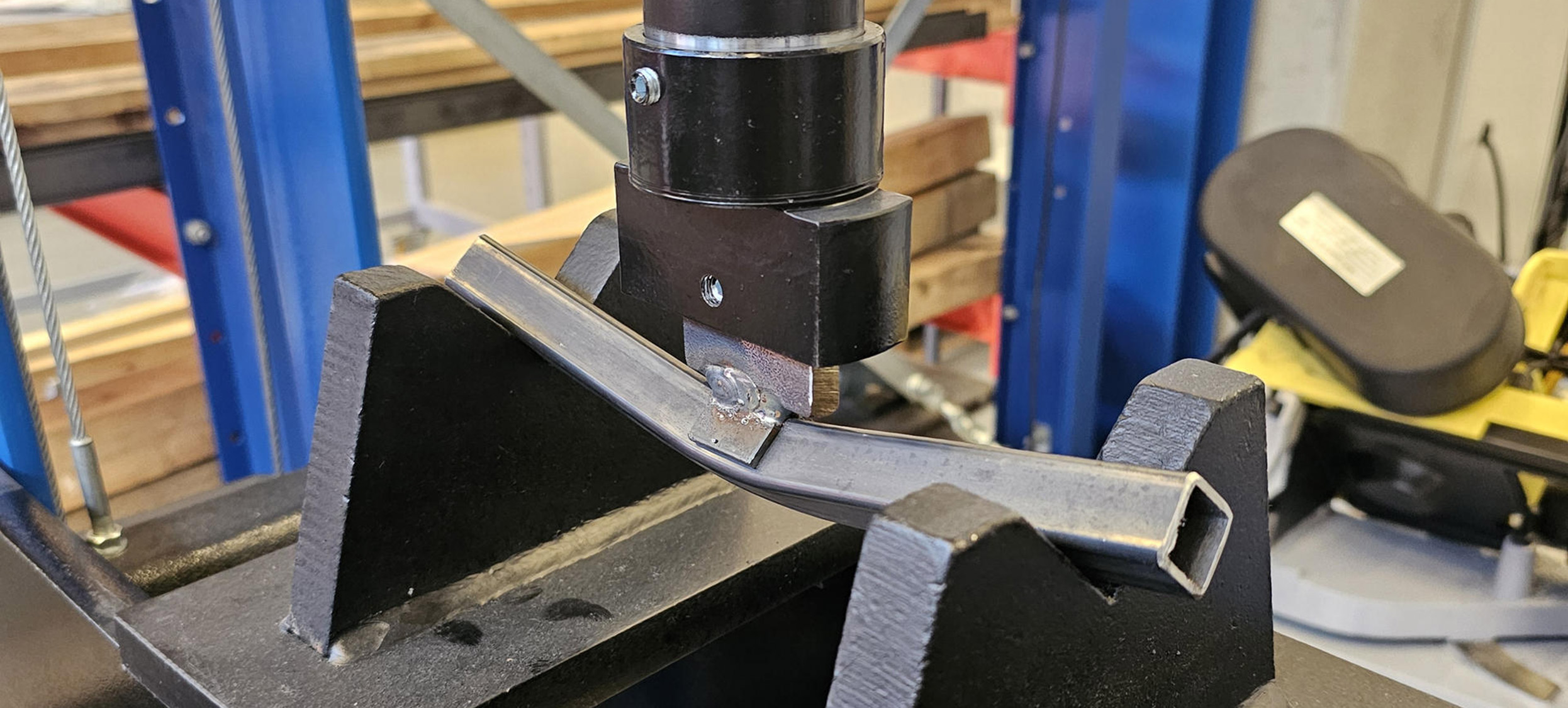 Eine Maschine belastet mit Druck ein Stahlprofil und überprüft die Querschnittstragfähigkeit