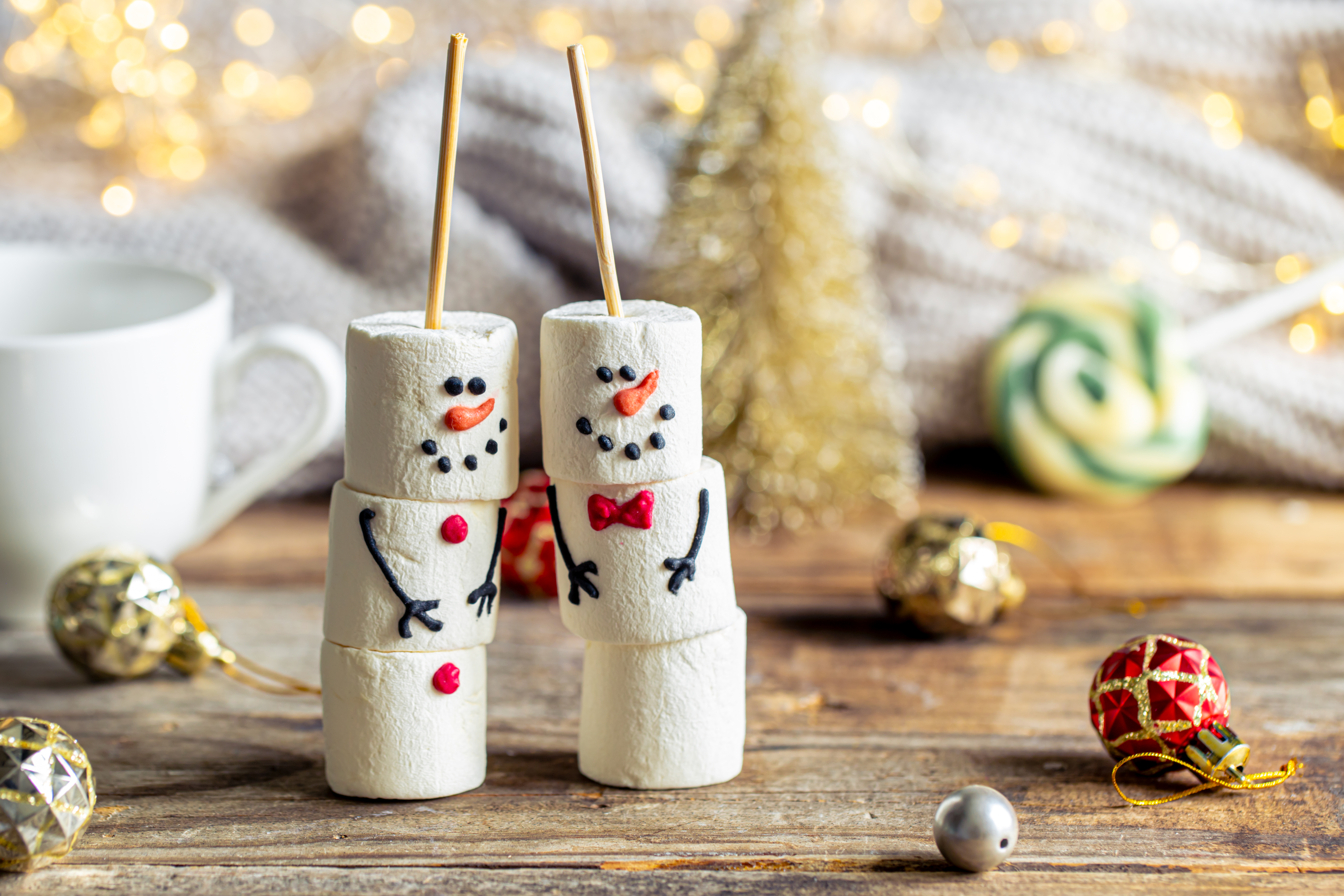 zwei marshmallow-figuren mit weihnachtlichem Hintergrund
