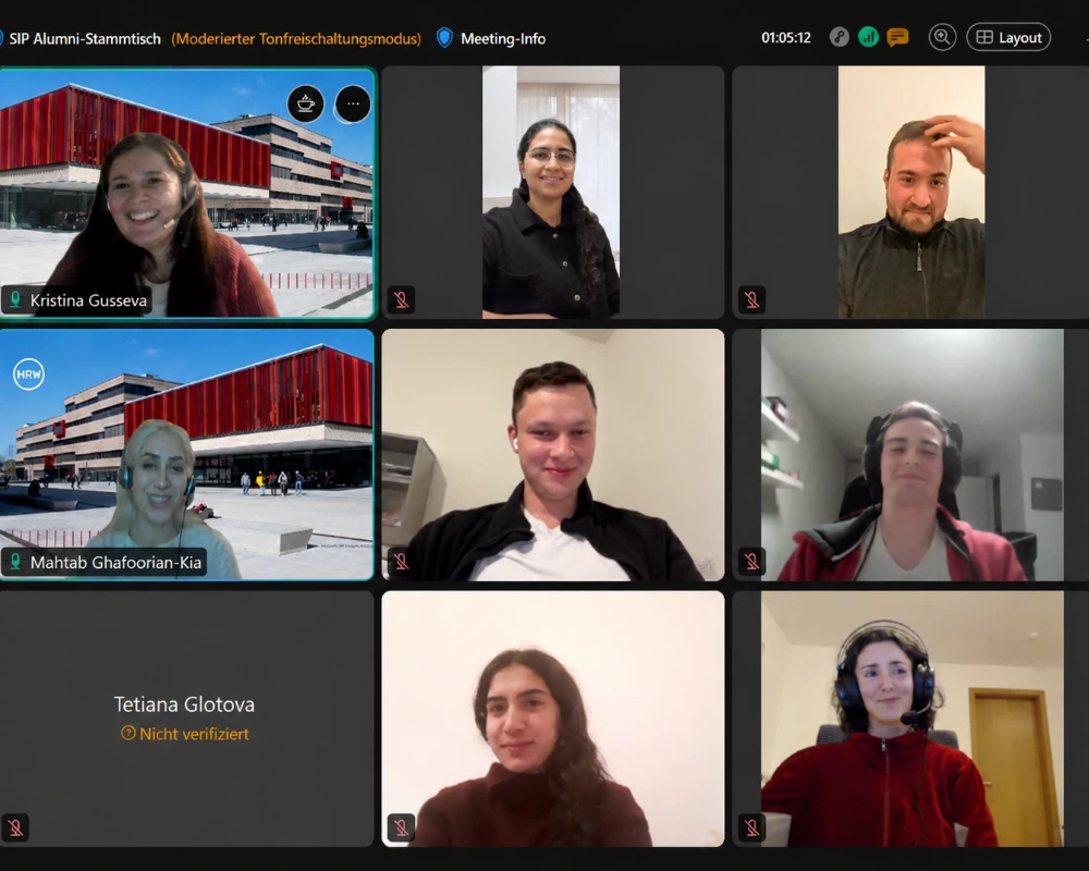 Screenshot einer Videokonferenz mit acht Teilnehmenden; lächelnde Gesichter in Kacheln, UI-Elemente und virtuelle Hintergründe sichtbar.