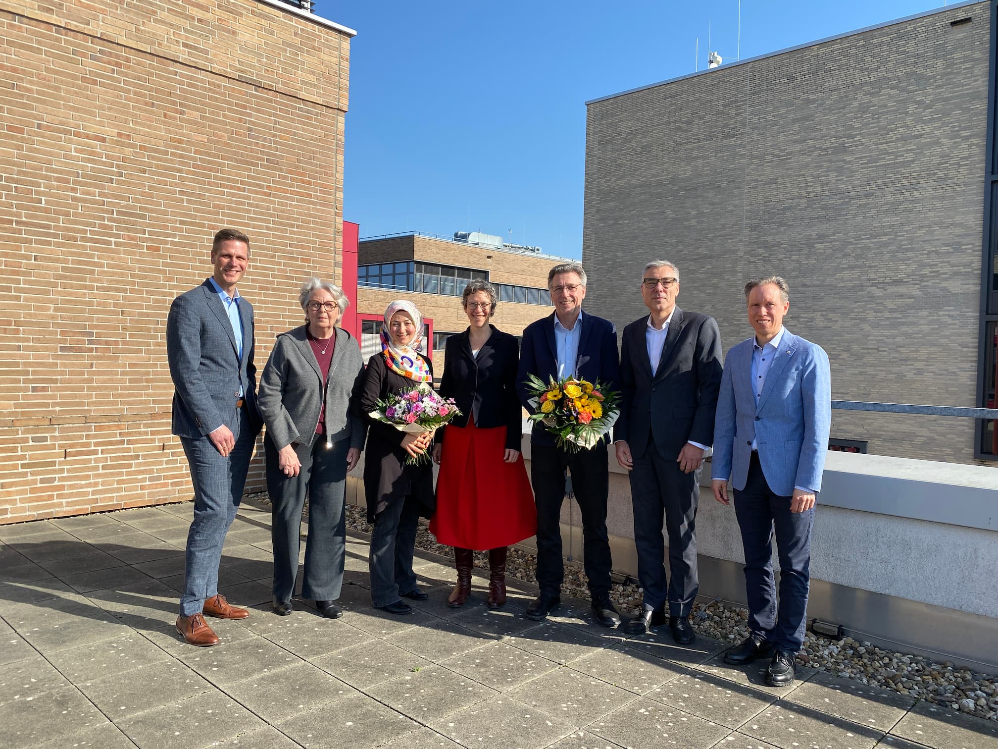 Sieben Männer und Frauen, die auf dem Campus der Hochschule Ruhr West stehen.