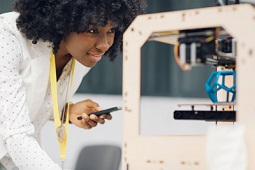 Eine Frau überwacht einen 3D-Drucker.
