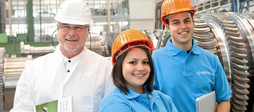 Das Bild zeigt zwei duale Studierende sowie einen Mitarbeiter aus einem Unternehmen.