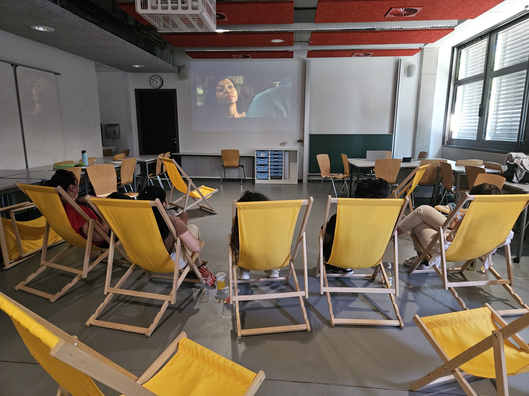 Fimvorführung der dezentralen Gleichstellung im Hörsaal, Personen liegen in gelben Liegestühlen.