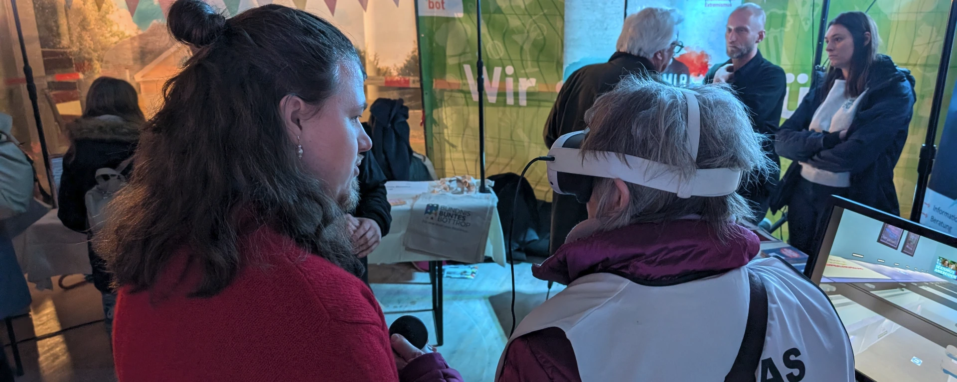 Mehrere Männer und Frauen, teilweise mit VR-Brille, in einem Veranstaltungsraum.