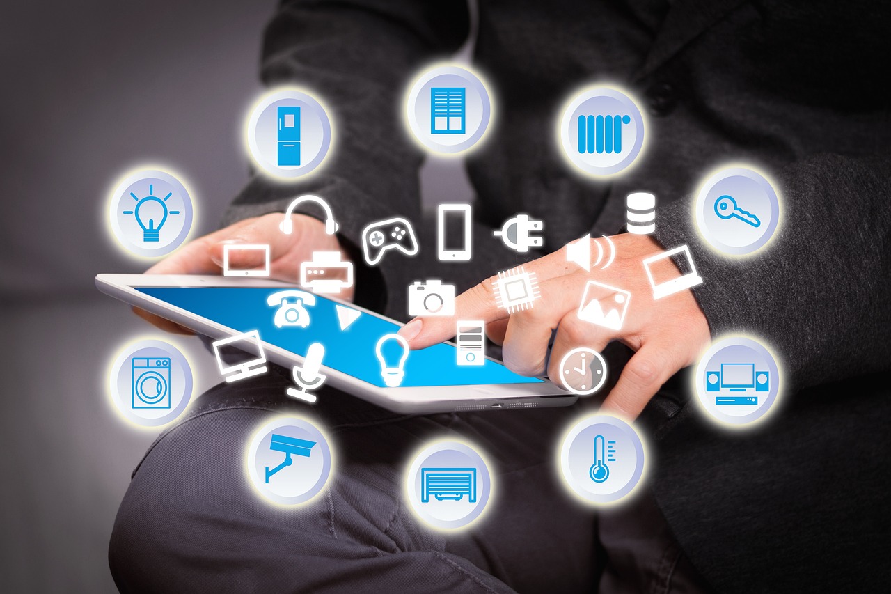 Eine Person in dunkler Kleidung hält ein Tablet, von dessen Bildschirm verschiedene Symbole für Smart Home und Technologie schwebend hervorgehen. Zu den Symbolen gehören eine Glühbirne, eine Batterie, ein Schlüssel, ein Zahnrad, eine Überwachungskamera, eine Heizung und andere Geräte, die auf eine vernetzte und automatisierte Umgebung hinweisen. Dieses Bild kann die Konzepte des Internets der Dinge, der Hausautomation oder des Smart Home Managements illustrieren.