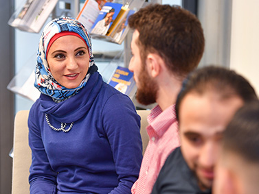 Studierende mit Kopftuch im Gespräch mit einem Studenten