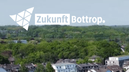 Foto: Schriftzug "Zukunft Bottrop" vor einer Wohnkulisse mit Grünflächen.