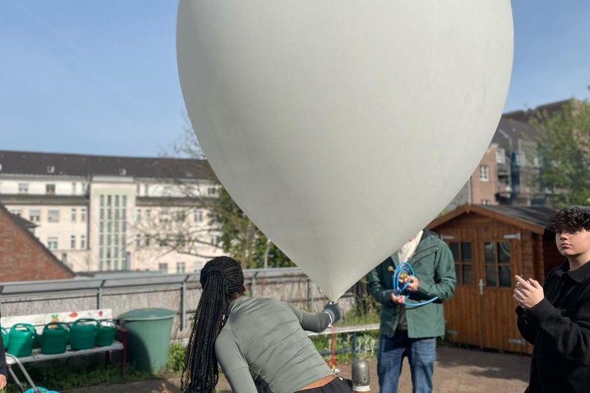 Jugendliche machen einen großen weißen Ballon bereit für den Start