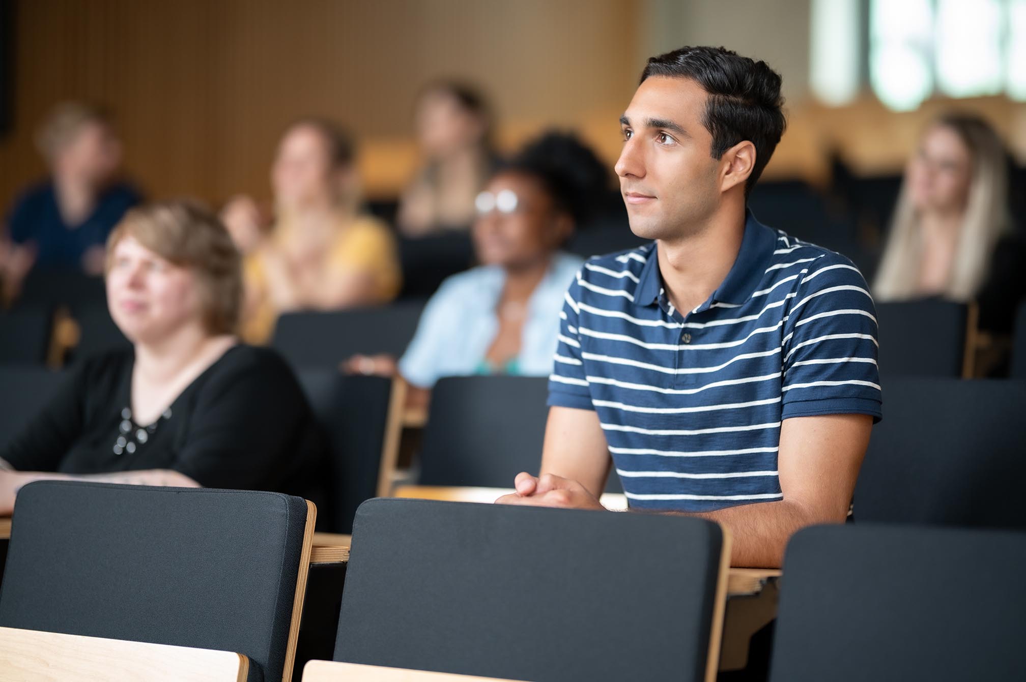 Ein Student in einem Hörsaal mit anderen Studierenden im Hintergrund auf dem Campus Bottrop.