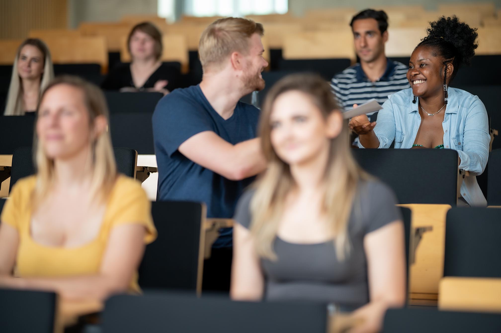 Mehrere Personen sitzen in einem Hörsaal und unterhalten sich