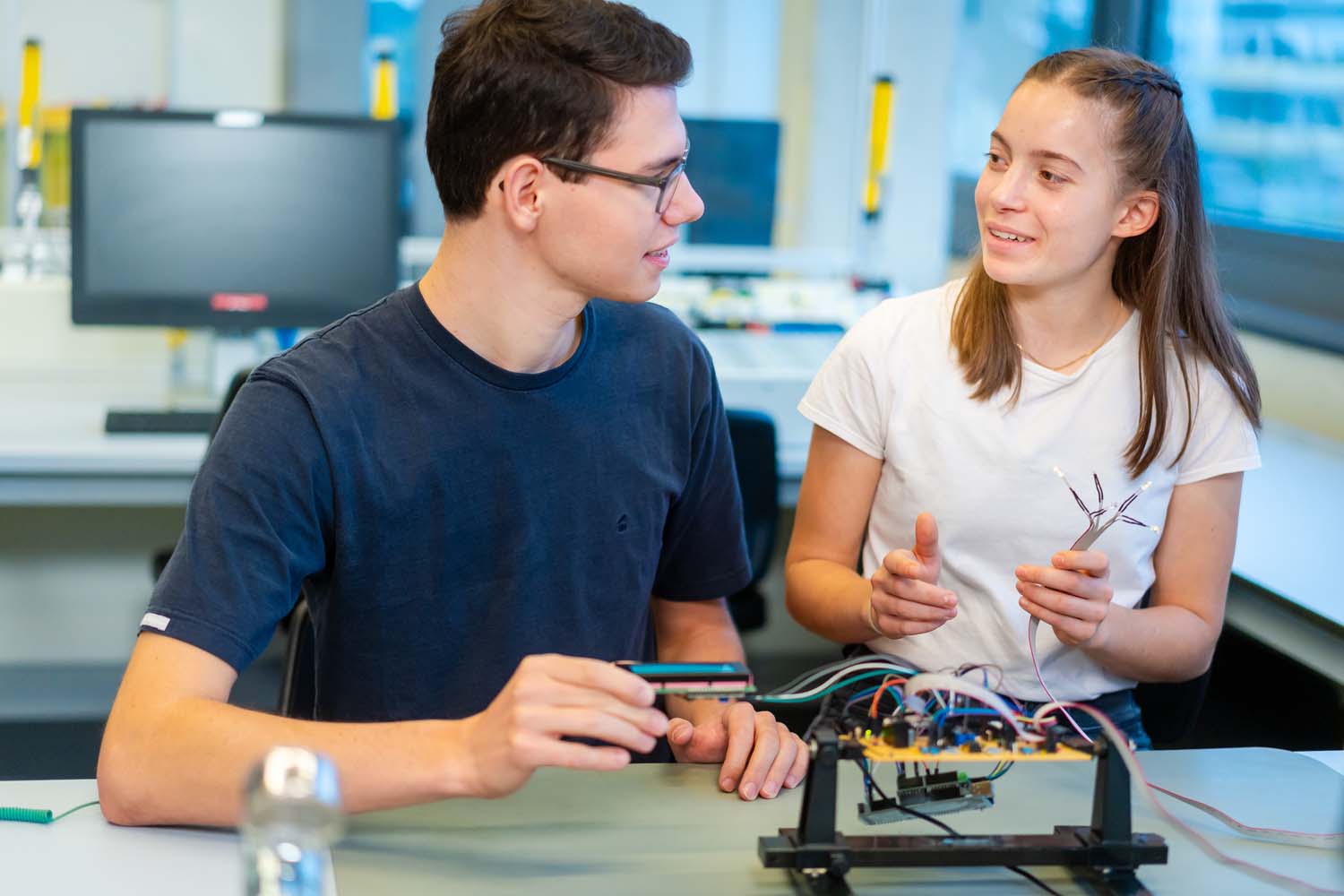 Zwei Studierende arbeiten an einer Platine.