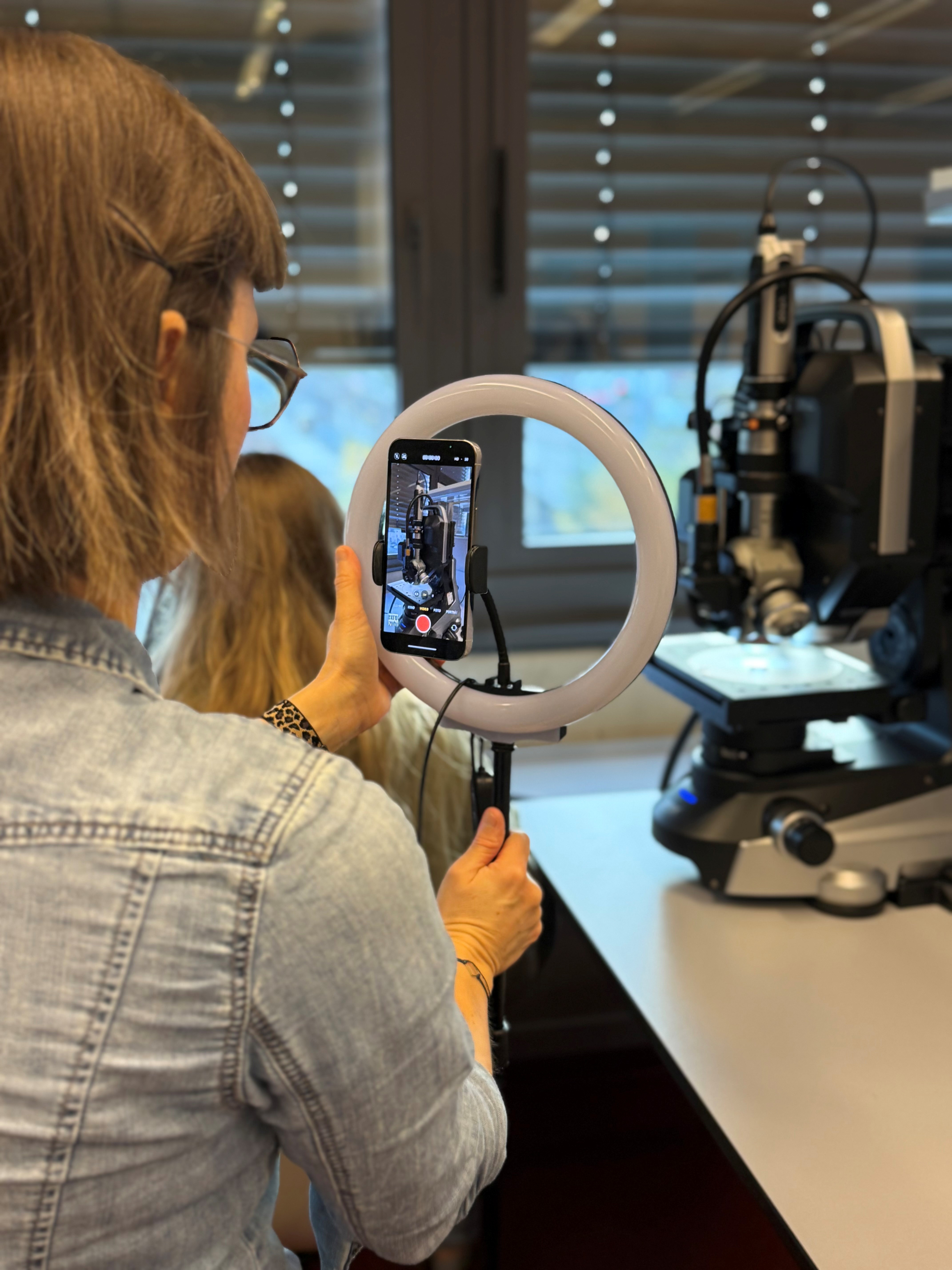 Redakteurin nimmt mit Handy und Lichtring eine Laboreinrichtung auf