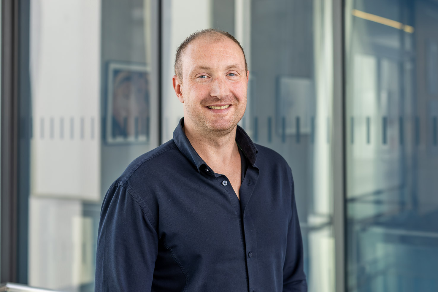 Pascal Brunke in dunklem Hemd vor Glaswänden im Büro.
