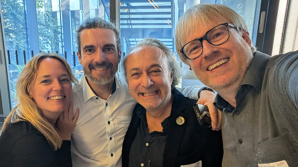 Auf dem Foto sind 4 Personen zu sehen, die in die Kamera lächeln.