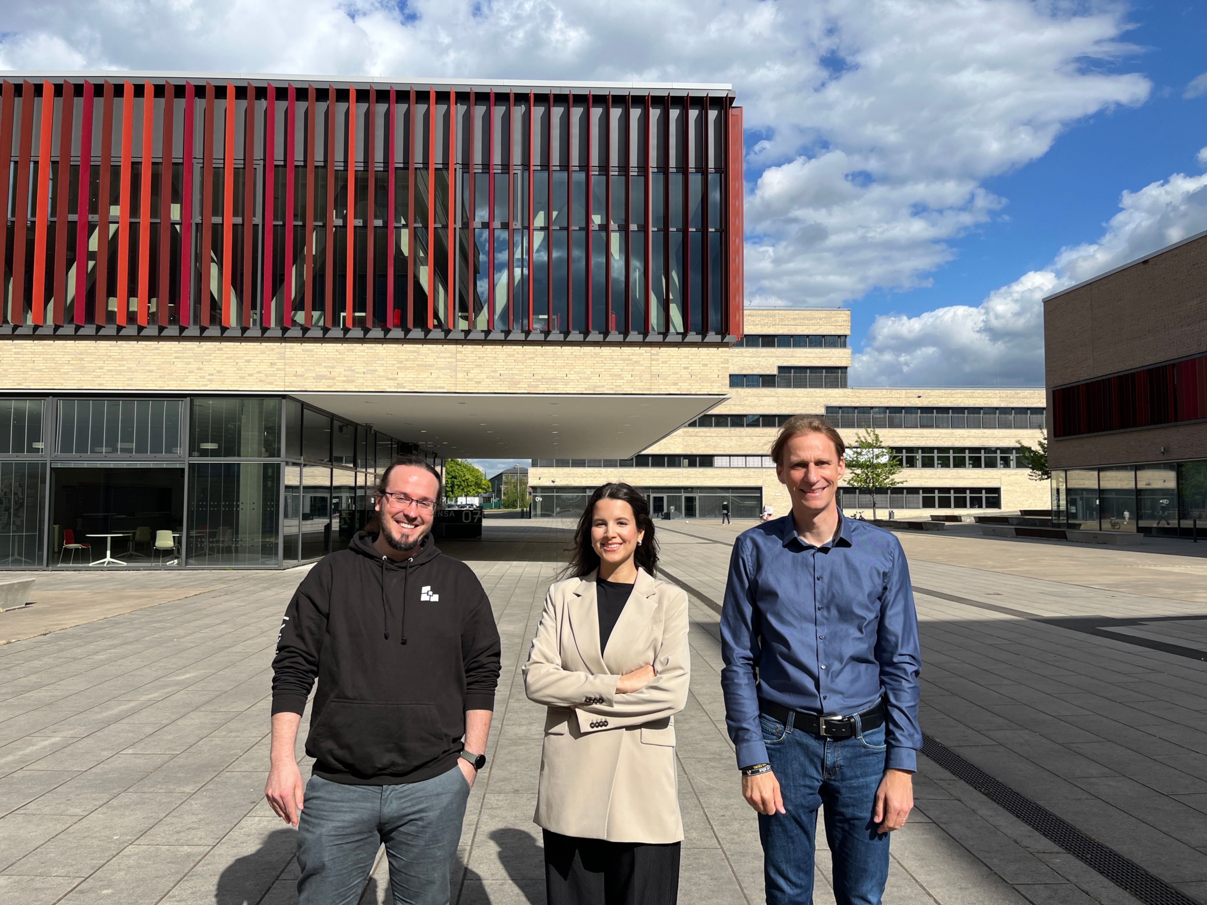 Eine Studentin steht zwischen zwei Männern auf dem Campus der Hochschule Ruhr West in Mülheim