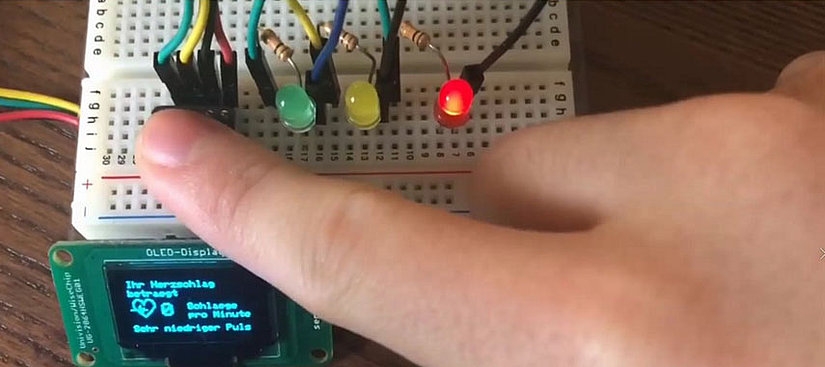 Breadboard mit LED-Lichtern und kleinem Monitor.