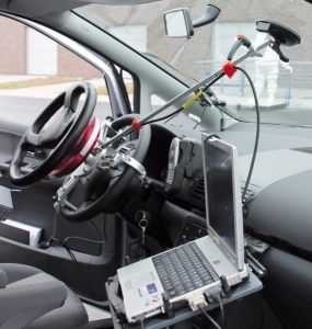 Innerres eines PKW. Am Lenkrad sind Messinstrumente angebracht. Daneben in Laptop.