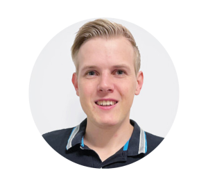 Ein junger Mann mit Blanden Haaren, der ein blaues Polohemd trägt, dessen Kragen mit Streifen abgesetzt sind