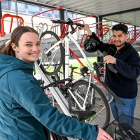 Eine Studentin und ein Student parken ihr Fahrrad im Fahrrad-Parkhaus.